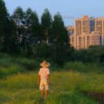 Man Standing in Forest with City Buildings behind