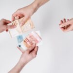 Someone giving cash pound notes with hands