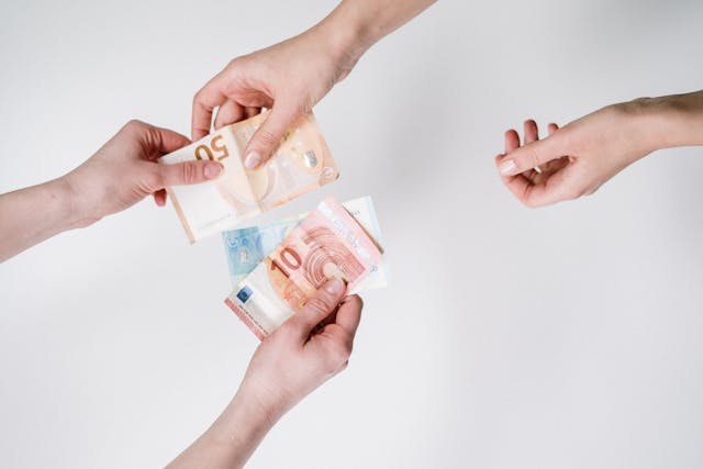 Someone giving cash pound notes with hands