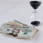 Hourglass near Heap of American Dollars