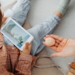 A Person's Hand Near a Kid Holding a Smartphone