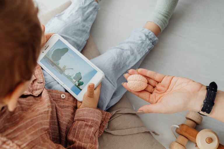 A Person's Hand Near a Kid Holding a Smartphone