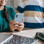 Faceless schoolchildren watching video on cellphone during break in classroom