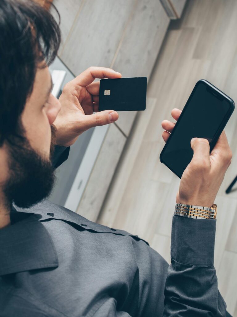 A man holding phone and credit card.