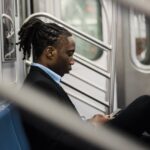 Serious male office worker using cellphone on subway train