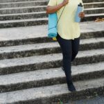 A Person Carrying Yoga Mat and Tumbler Going Down the Concrete Stairs