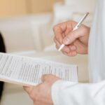 Photo Of Person Holding Paper And Pen