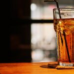 Clear Drinking Glass With Brown Liquid on Brown Wooden Table