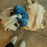 Backpack with Neck Pillow and Travel Bag Lying on Ground