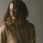 a girl with long hair wearing beige hoodie in a movement