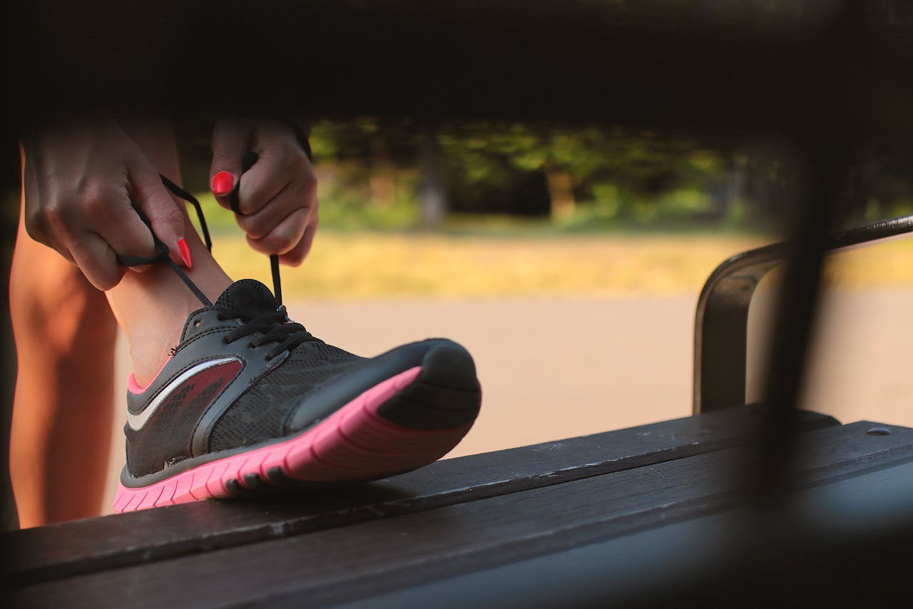 Woman tying her running shoes at sunrise, symbolizing a fresh start after a health or fitness break.