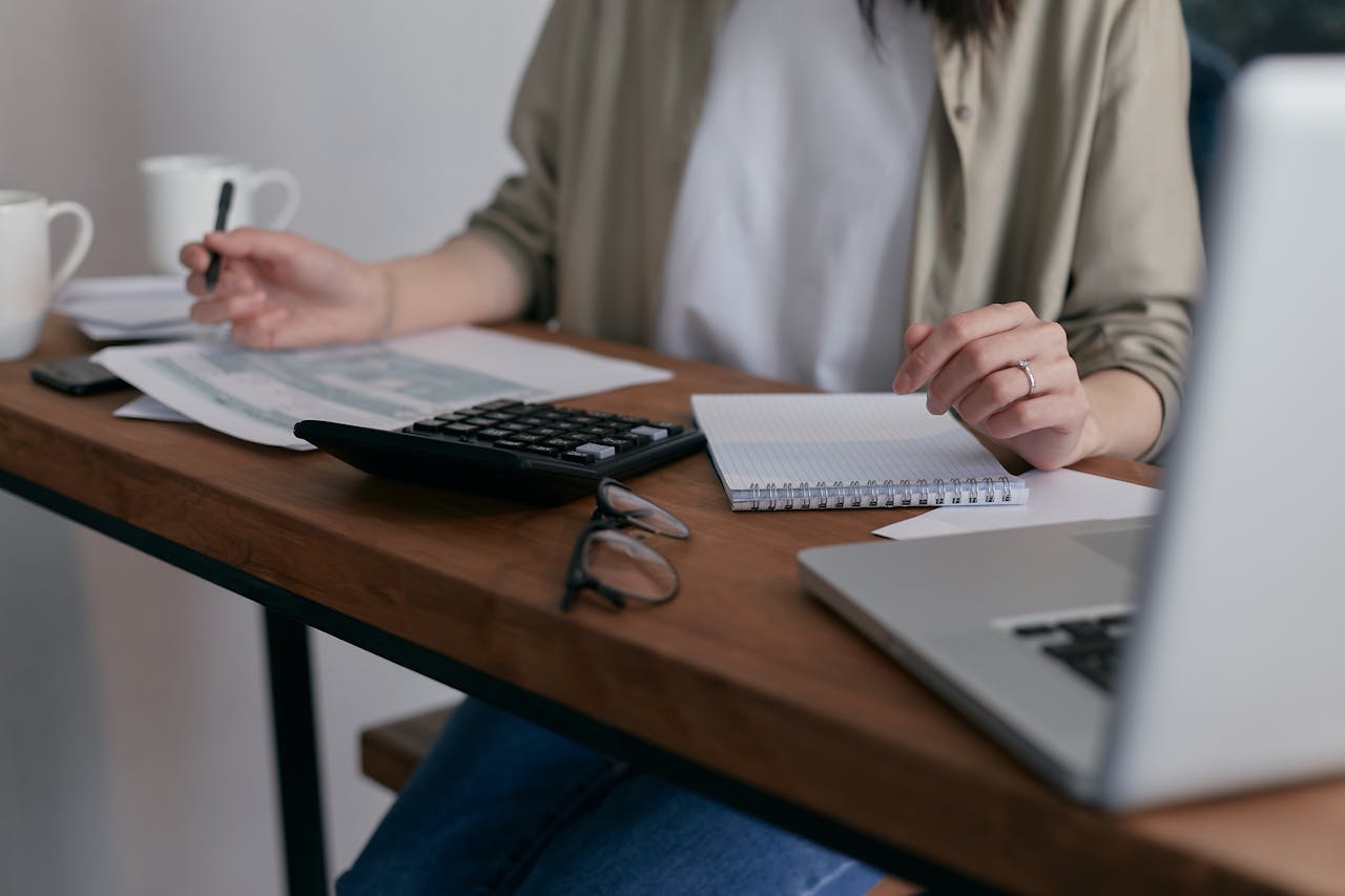 Person sitting on the chair surrounded by bills, feeling stressed about debt.